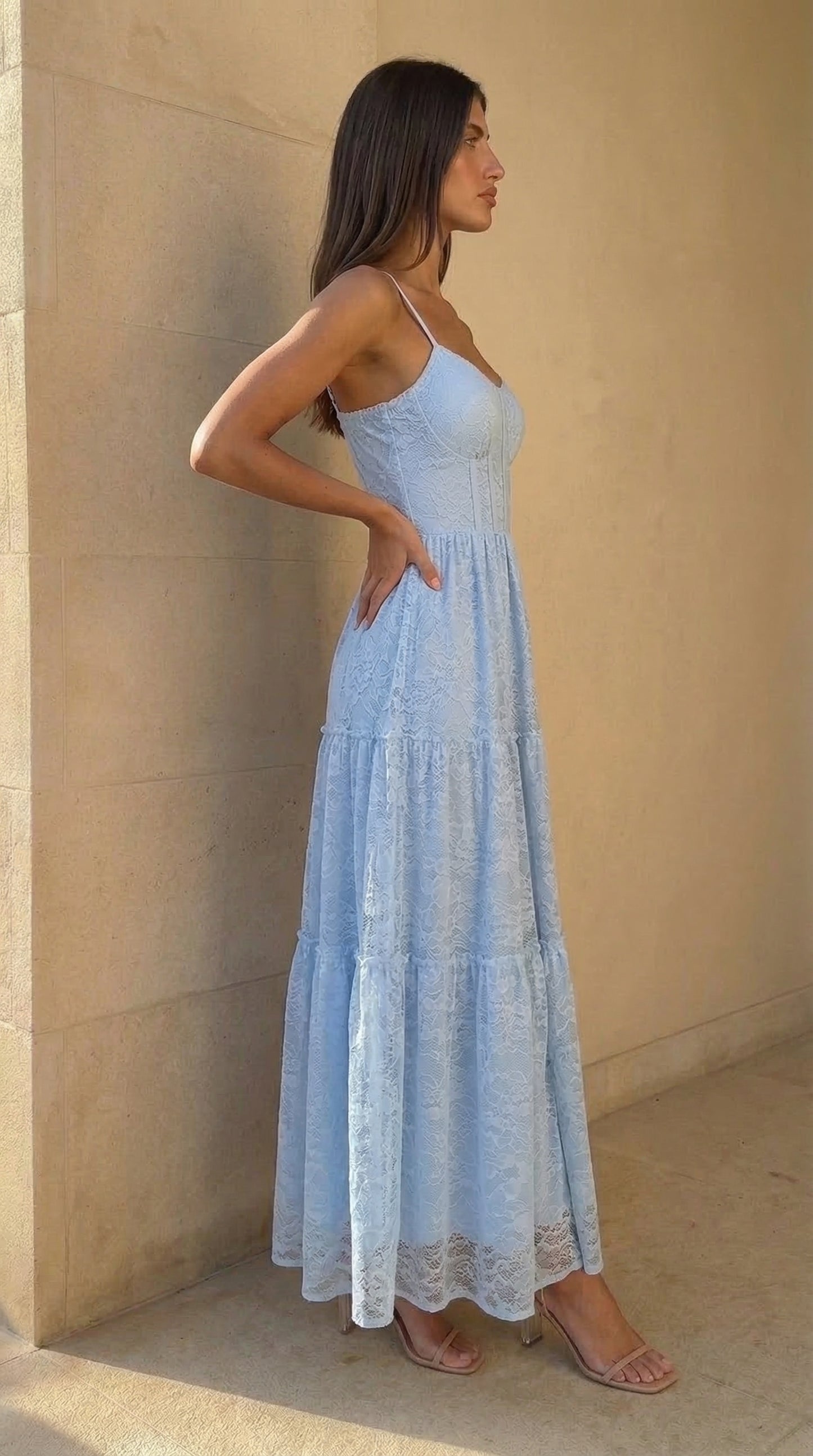 Woman wearing a light blue dress standing against a beige wall.
