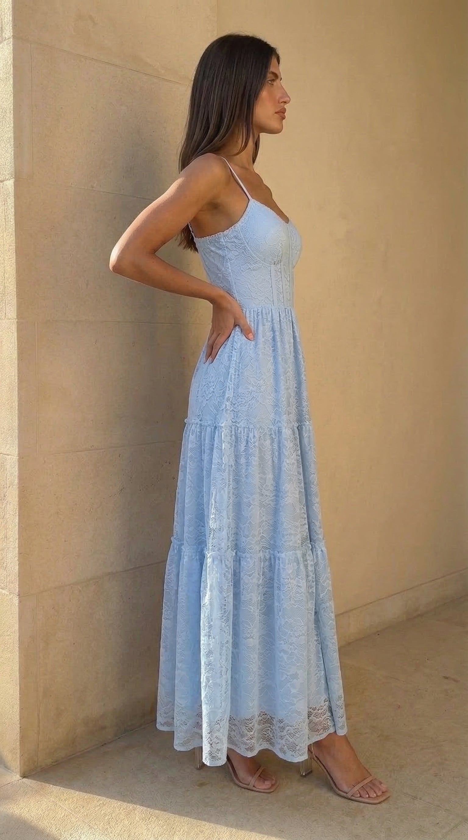 Woman wearing a light blue dress standing against a beige wall.